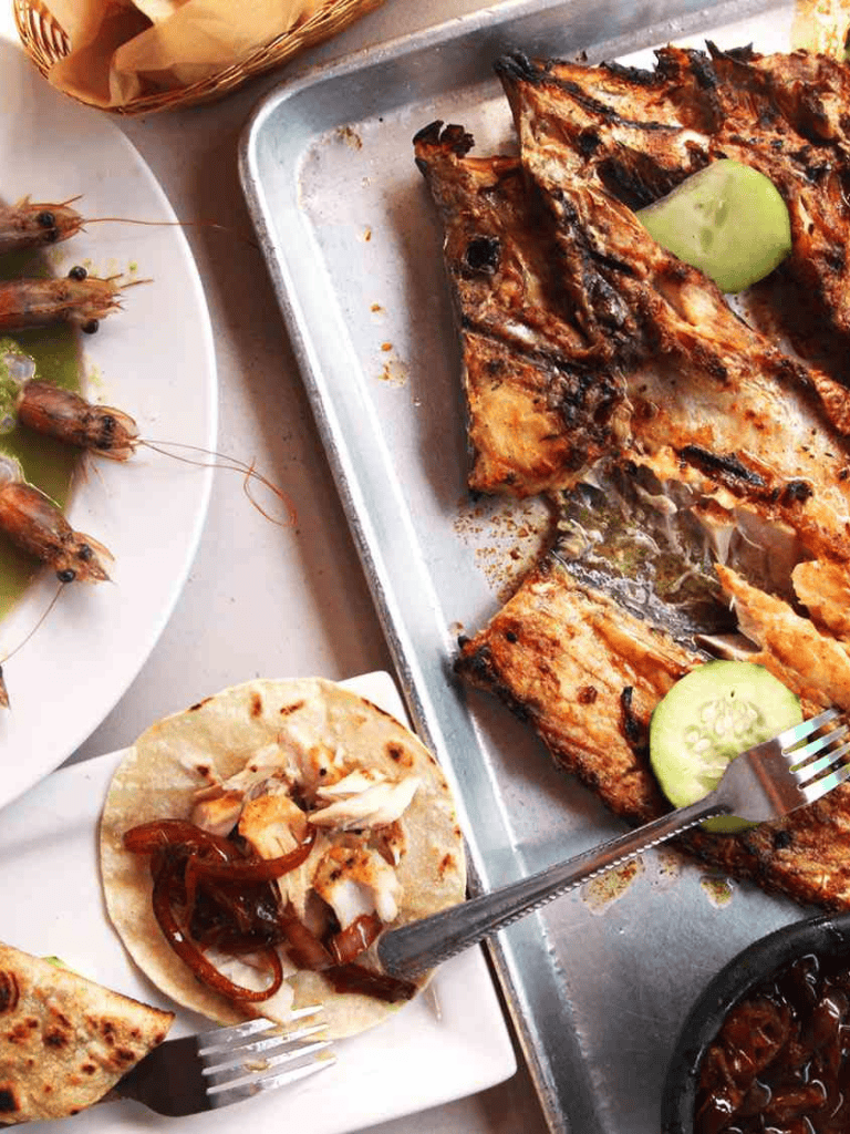 Grilled fish with cucumber slices and shrimp tacos at a restaurant.