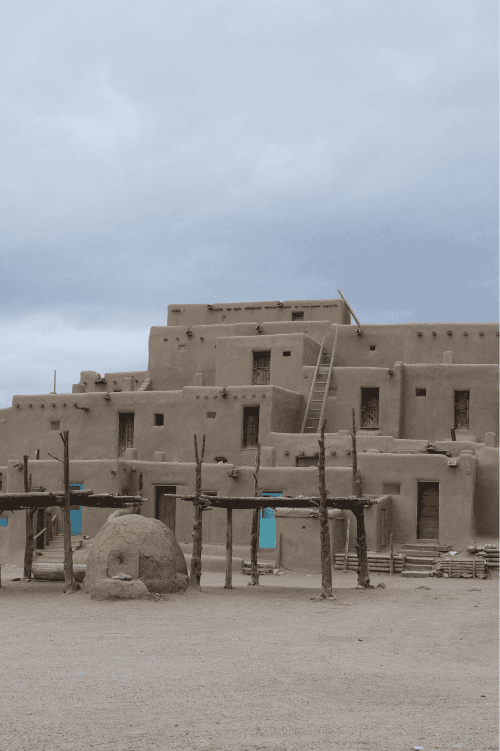 Ancient adobe village with traditional architecture and wooden scaffolding in a desert setting.