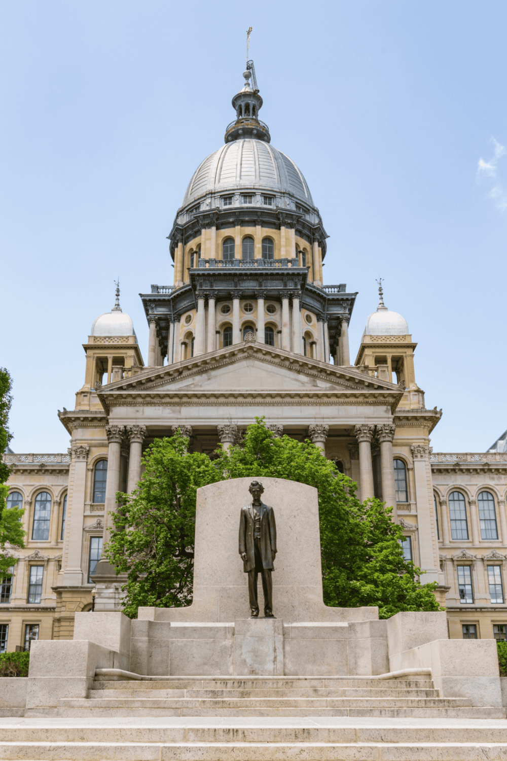 Historic state capitol building with a statue in front, emphasizing government, history, and architecture.