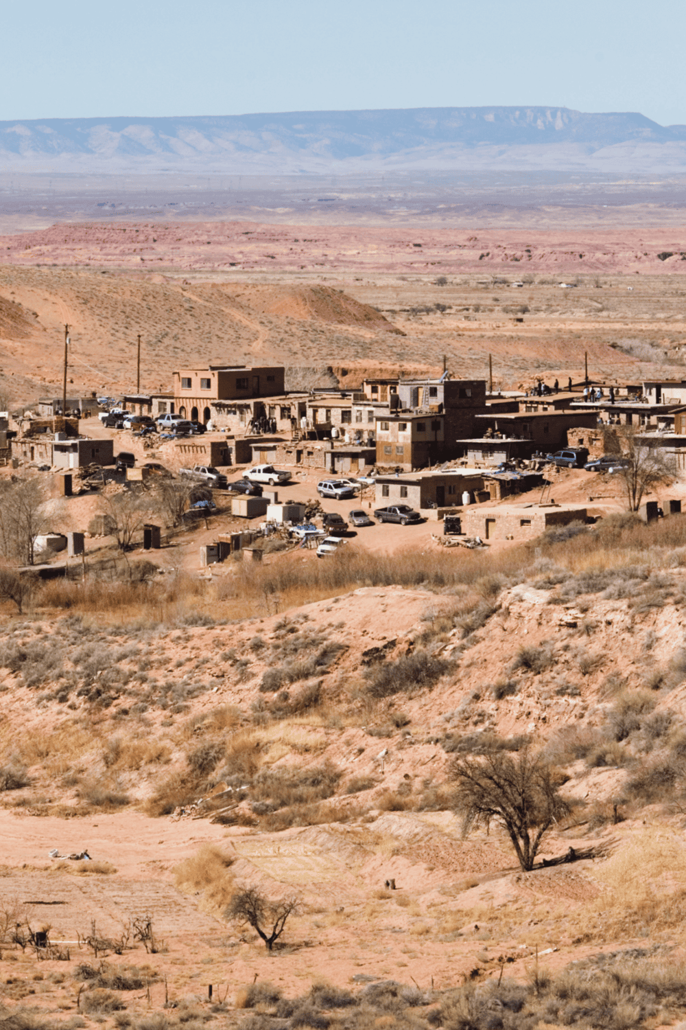 Dry desert landscape with remote housing and multiple cars in Quest for Directions image.