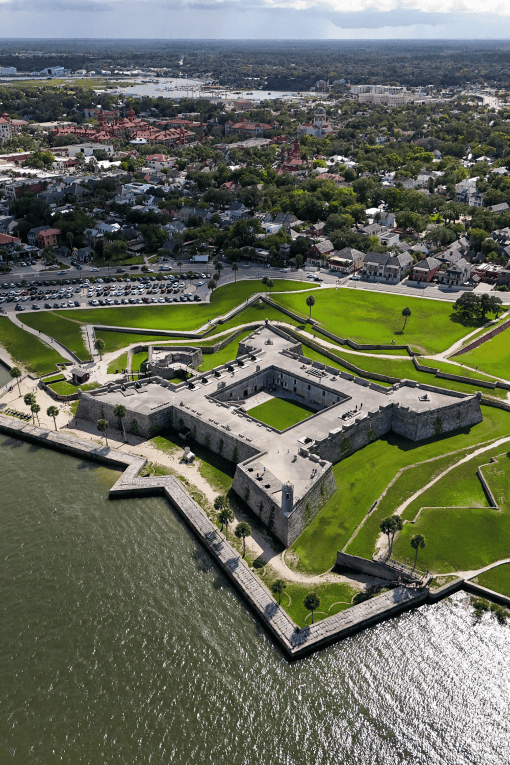 Historic fort on waterfront with surrounding cityscape and marina in the background.