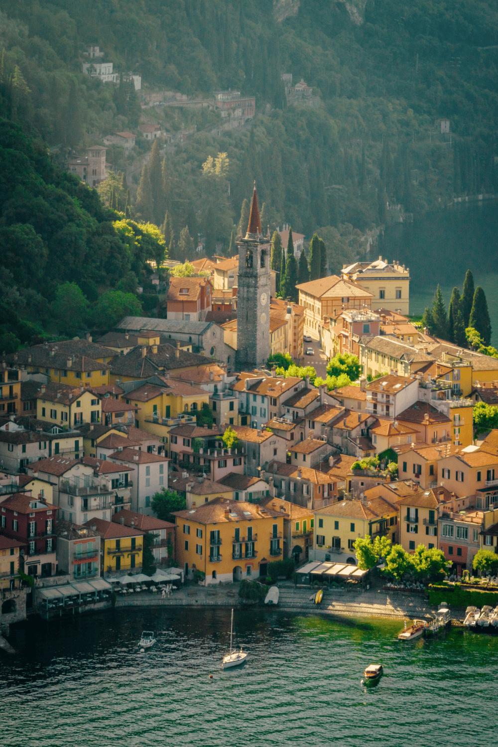 Colorful lakeside Italian village with historic church and boats on the water.