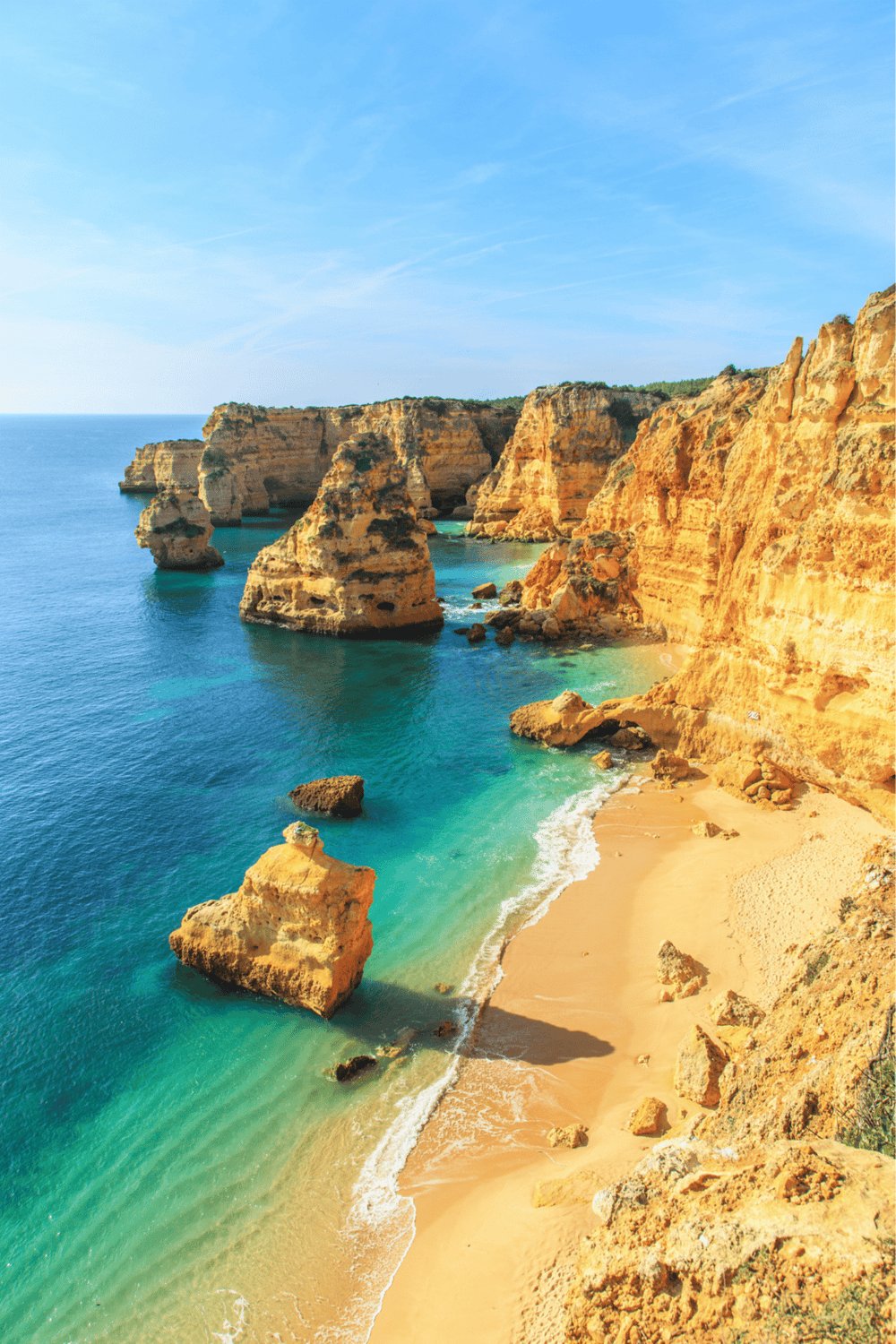 Cliffs and rock formations along a golden sandy beach at Portugal's Algarve coast.