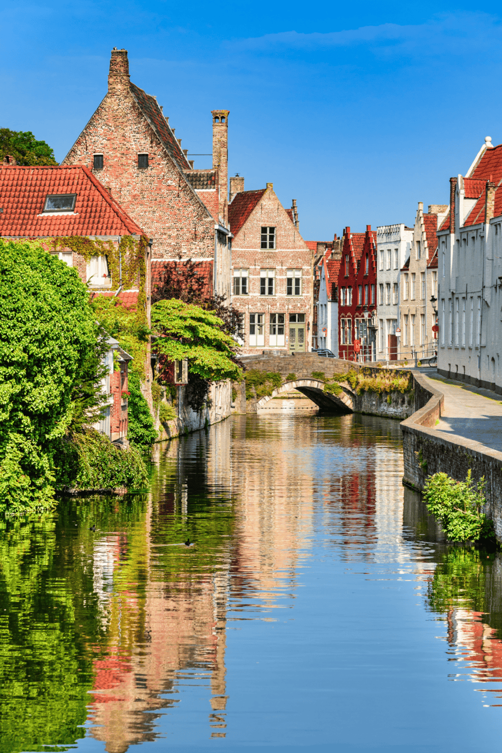 Quaint European canal town with historic brick buildings and lush greenery, perfect for sightseeing and travel.