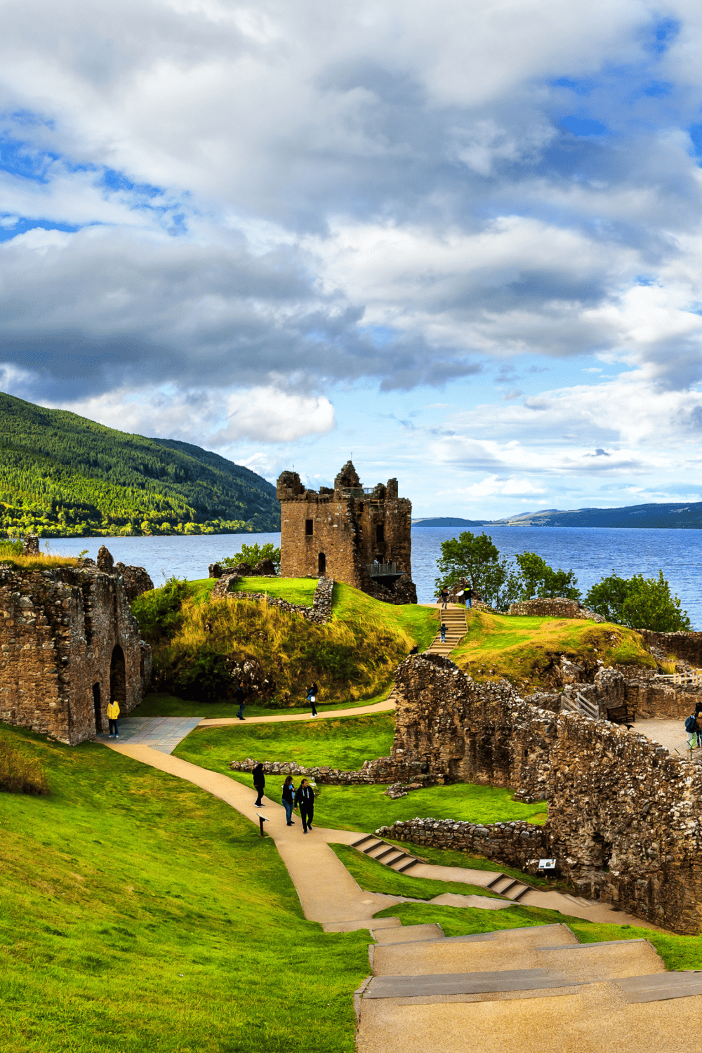 Medieval castle ruins on Loch Ness, Scotland, with scenic landscape and cloudy sky.