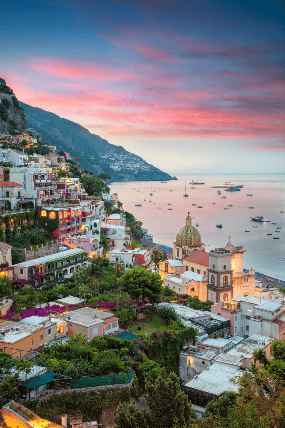 Colorful Amalfi Coast hillside town with vibrant buildings and sunset over the Mediterranean Sea.