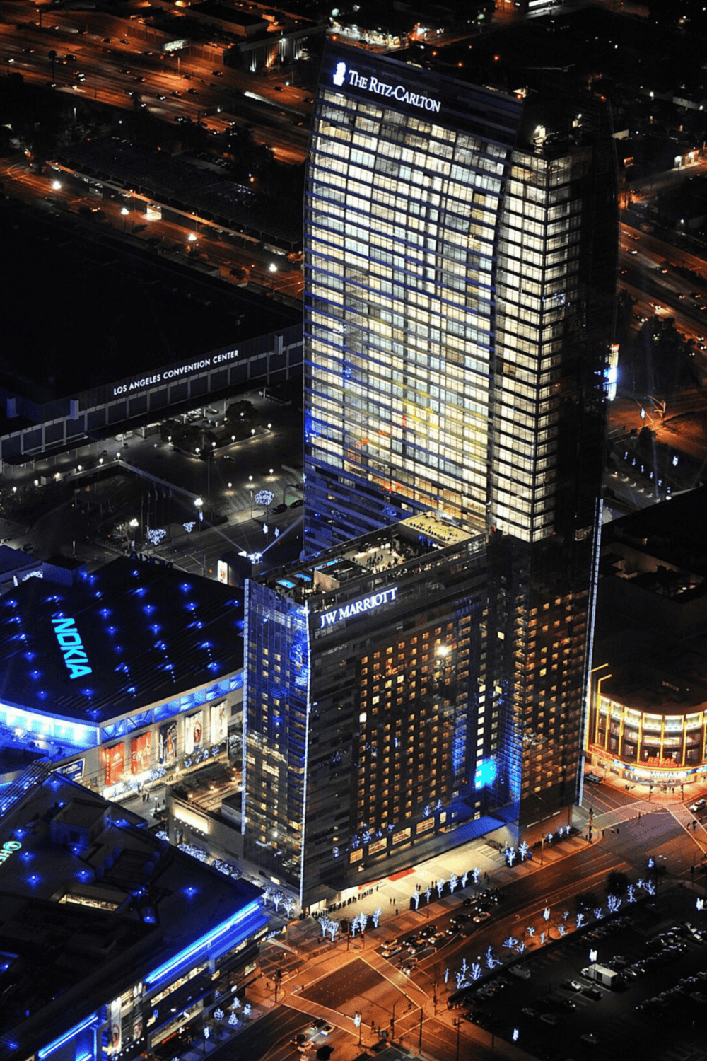 Brightly lit downtown Los Angeles skyscraper featuring JW Marriott and Nokia signage at night, promoting hotel accommodation and city views.