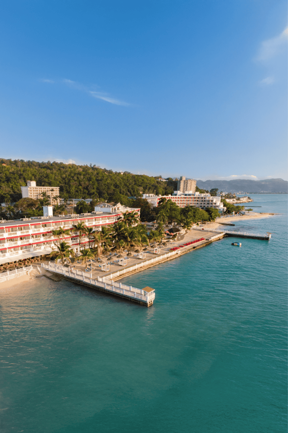 Aerial view of a beachfront hotel and marina in a tropical coastal destination, ideal for travel and vacation planning.