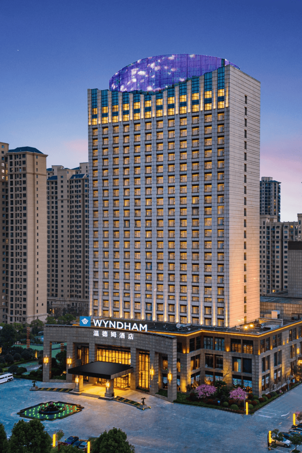 Elegant Wyndham hotel in downtown city skyline with illuminated windows at dusk.