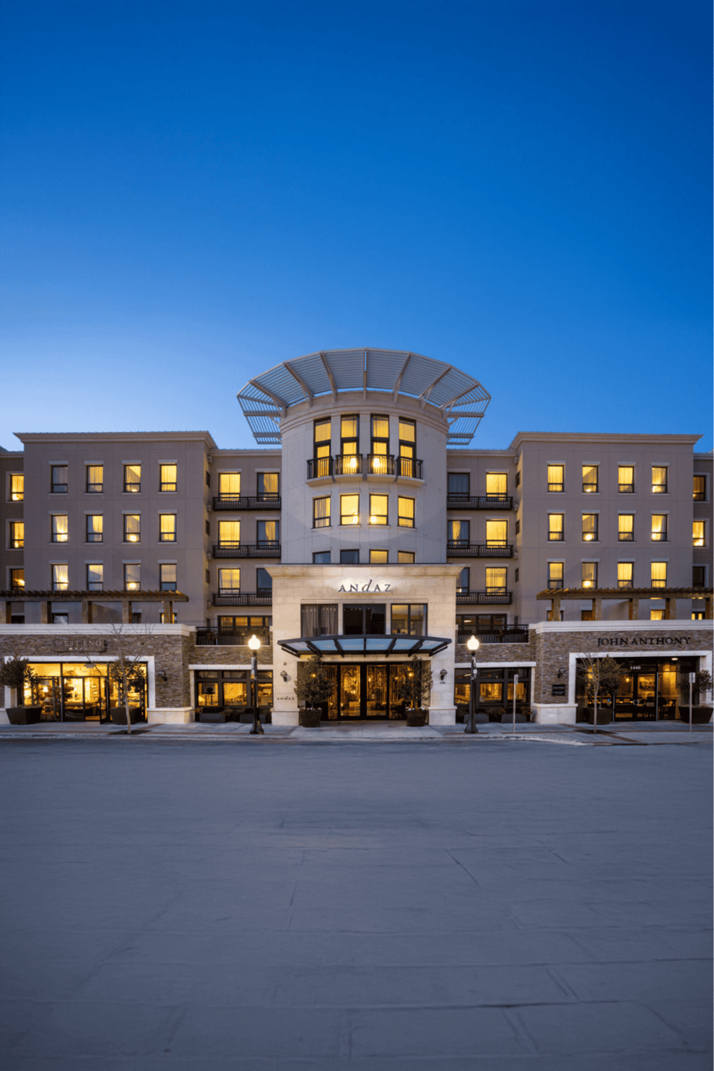 Modern luxury hotel exterior in the evening with illuminated windows and stylish entrance.