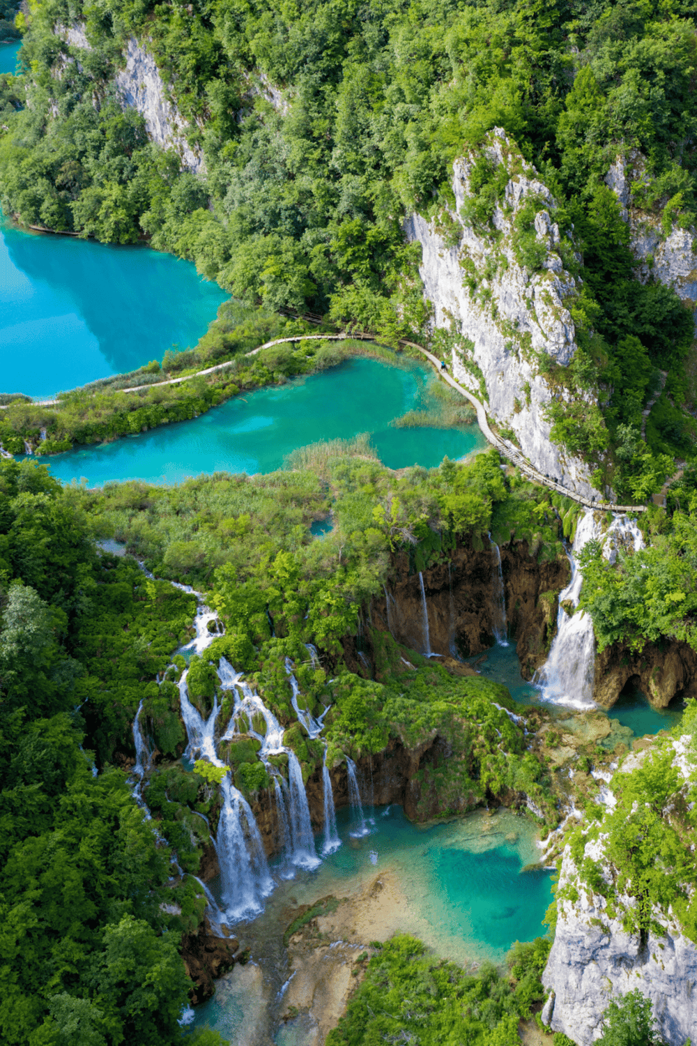Vibrant turquoise lakes and cascading waterfalls in lush green canyon, perfect for nature exploration.