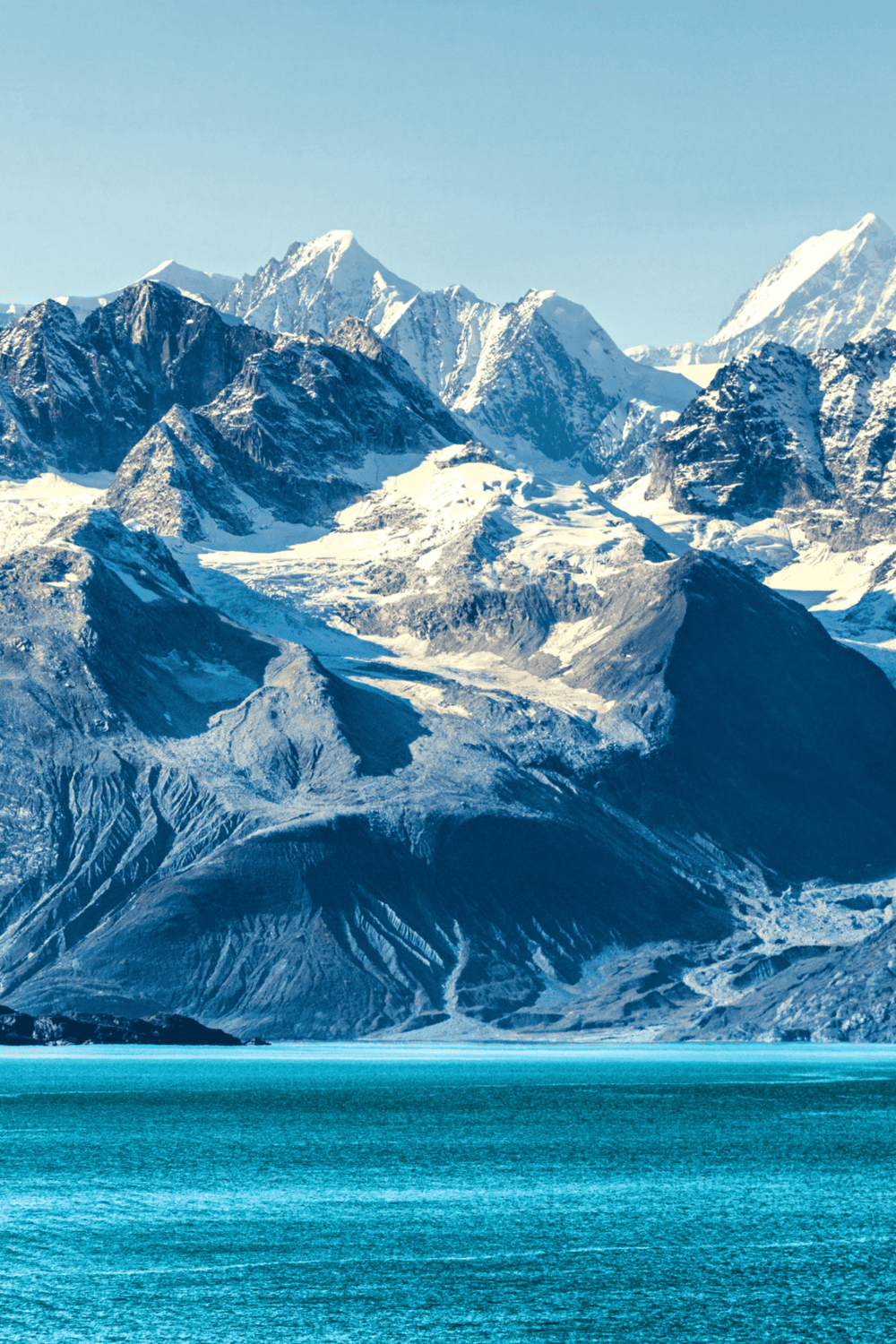 Snow-capped mountain range with glaciers and turquoise water, scenic landscape for outdoor adventures or travel.
