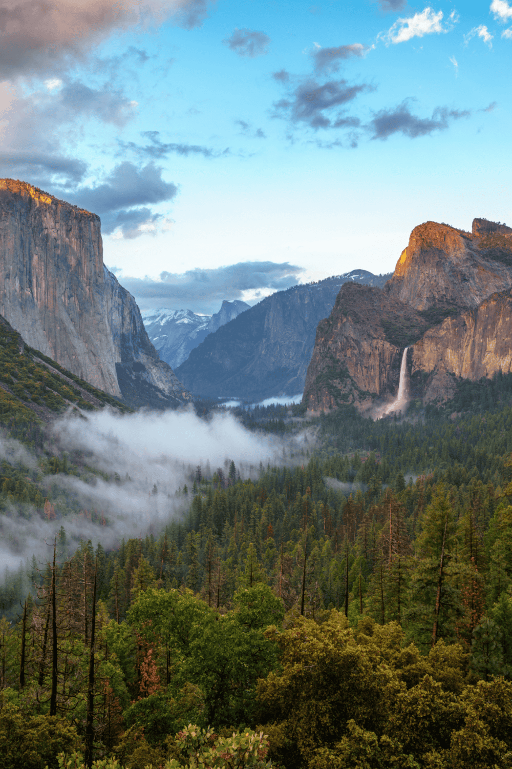 Majestic Yosemite Valley with towering cliffs, lush forest, and cascading waterfalls in national park.