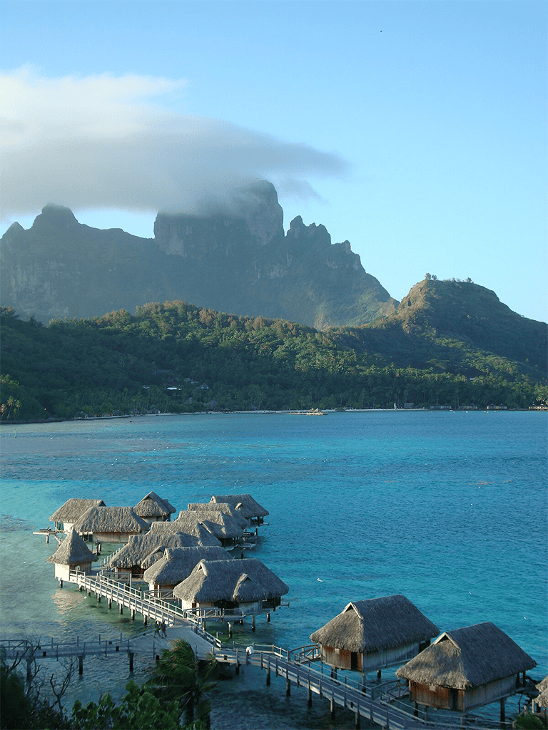 Stunning overwater bungalows in Bora Bora, French Polynesia, with lush mountains and clear blue waters.