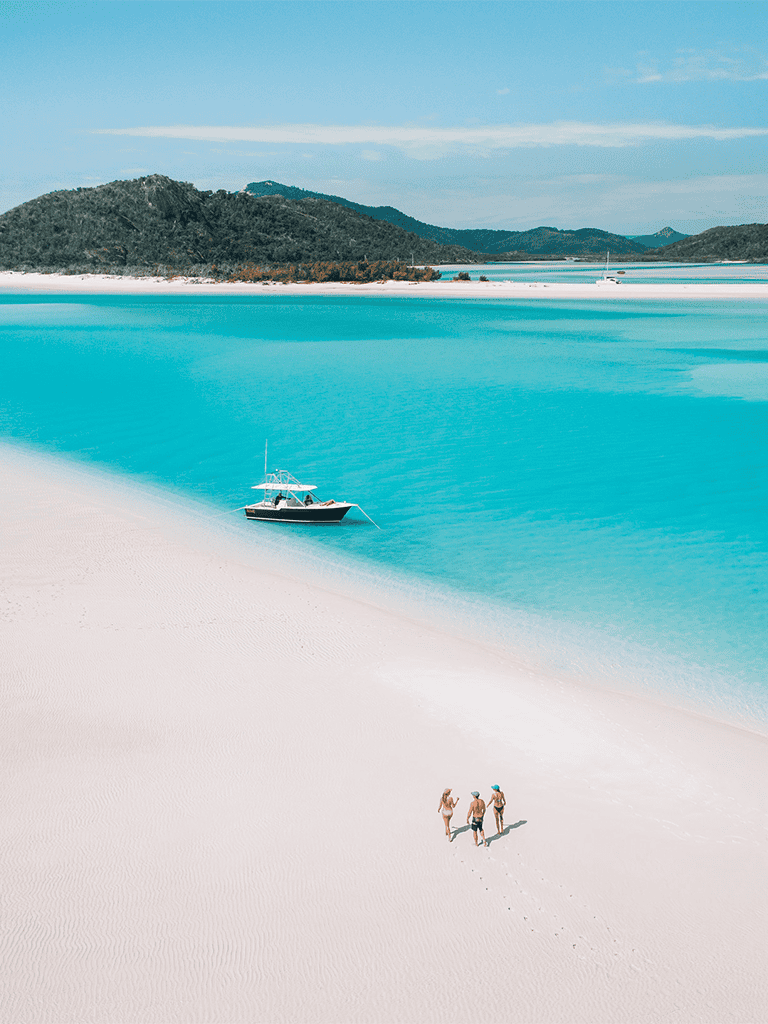 Pristine white sandy beach with turquoise waters and a boat, perfect for tropical getaway and beach adventures.