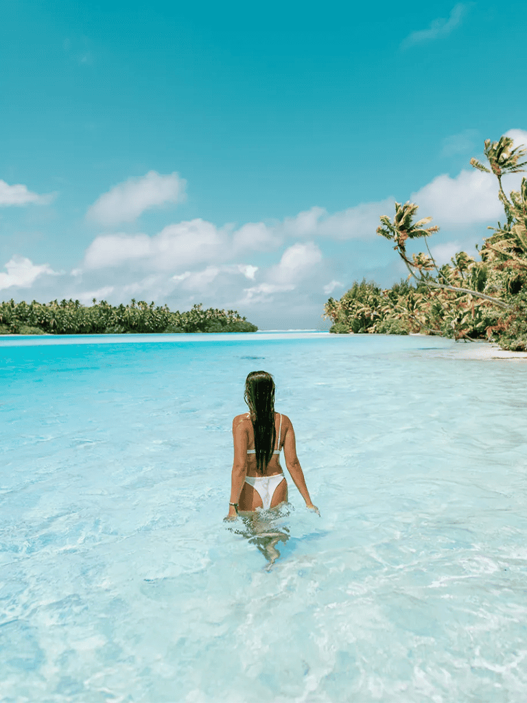 Serene tropical beach with clear turquoise water and lush palm trees under a blue sky.