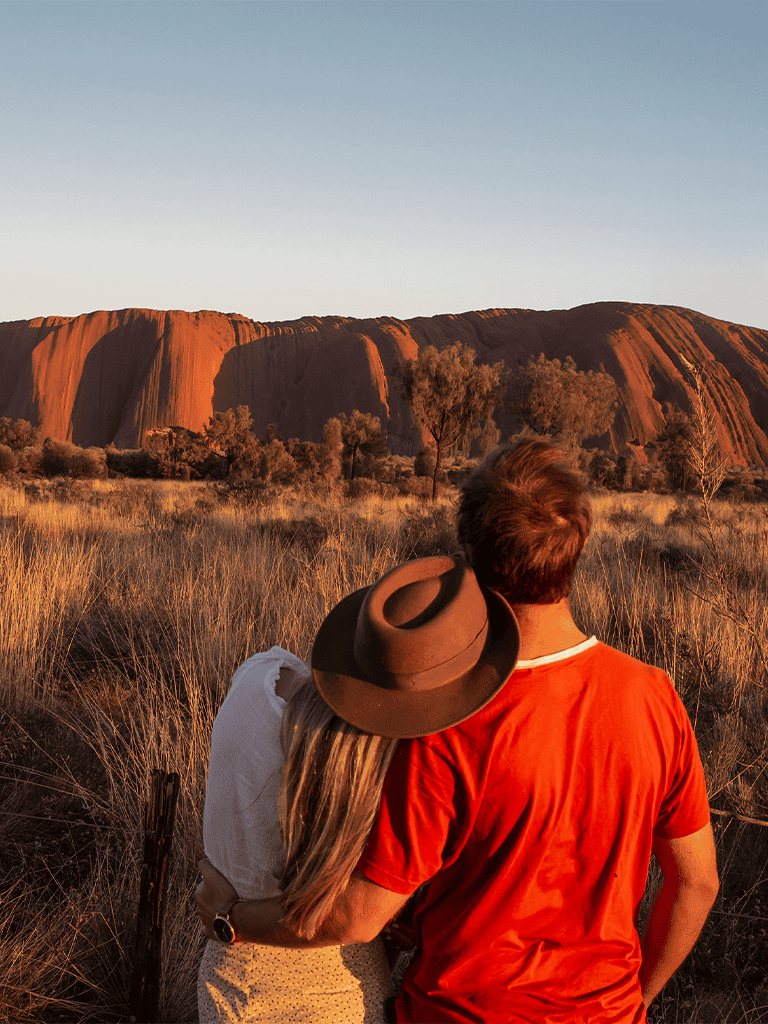 Explore iconic Australian Uluru at sunset with loved ones, experiencing natural beauty and adventure.