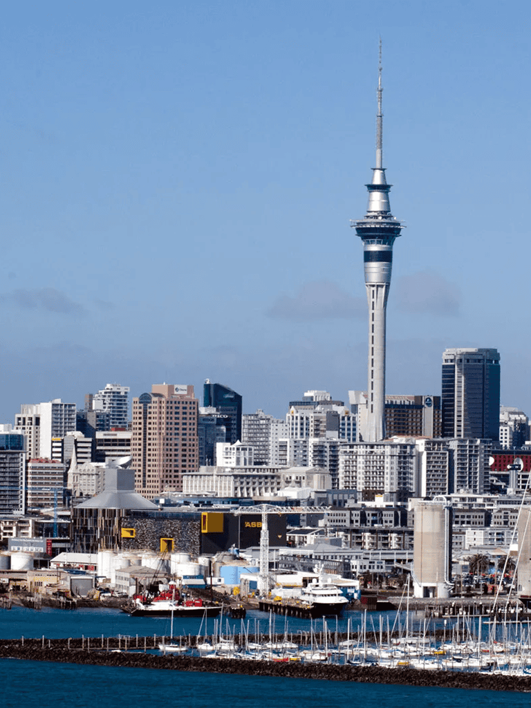 Modern Auckland skyline with Sky Tower and waterfront marina, New Zealand travel destination.