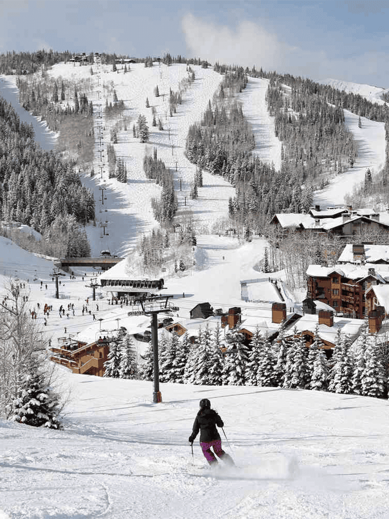 Snow-covered ski resort with skier descending the slope, scenic mountain backdrop, and cozy lodges, perfect for winter sports enthusiasts.