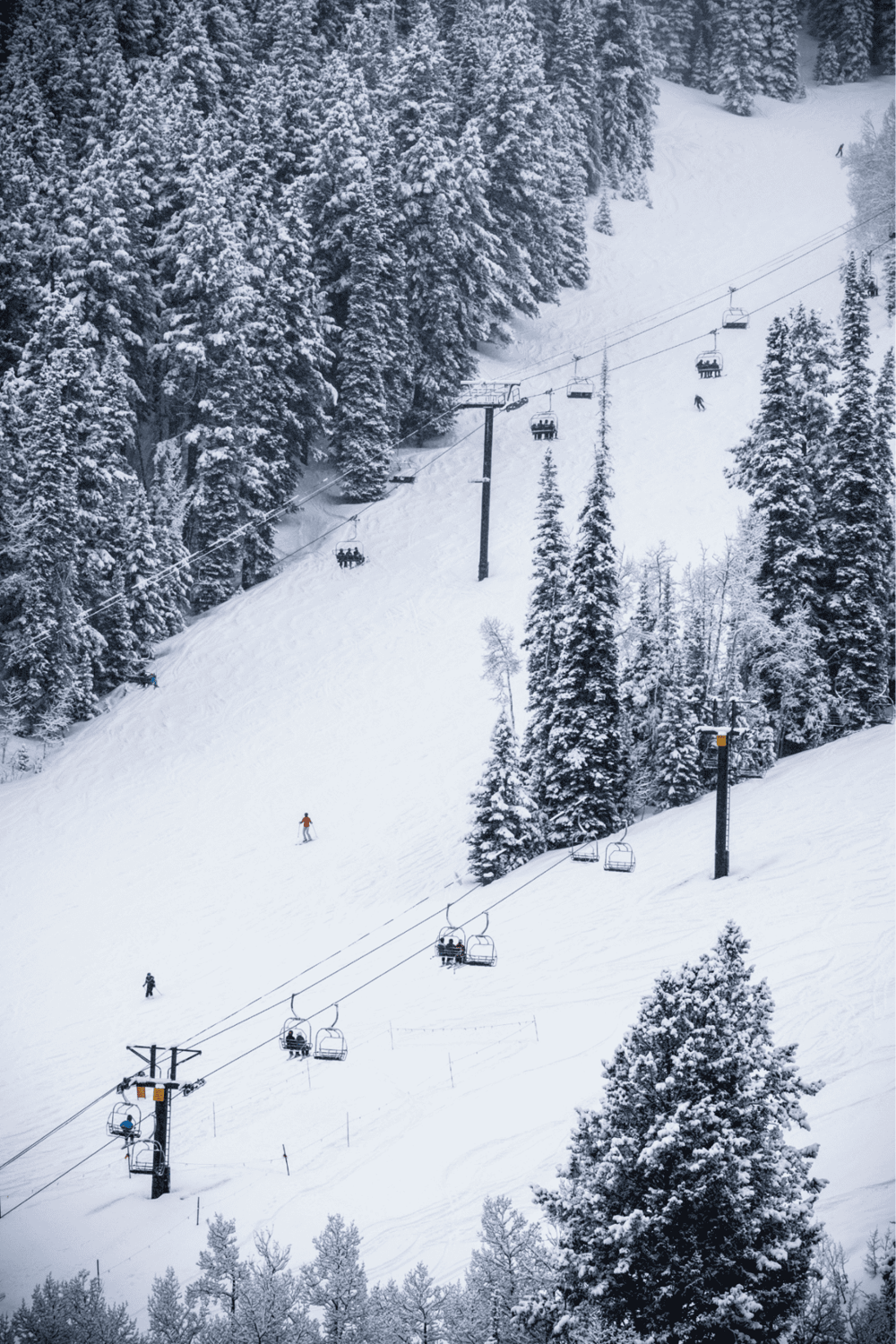 Snow-covered ski slope with ski lifts and skiers, ideal for winter sports and mountain adventure.