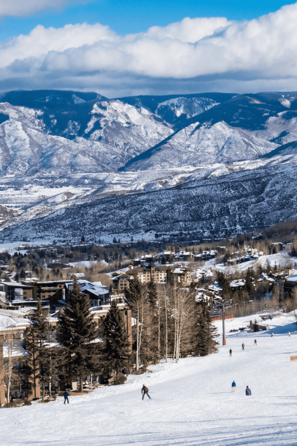 Snowy mountain scenery with ski resort buildings and skiers on the slopes.