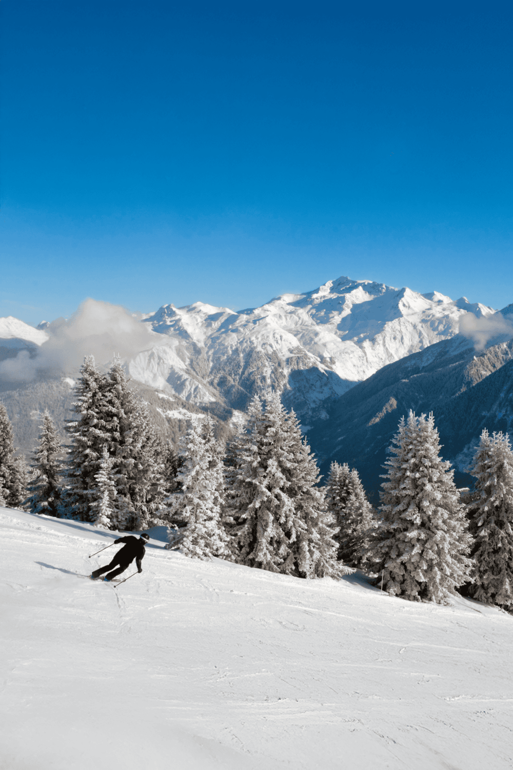 Snowy mountain landscape with skier in the foreground, perfect for winter sports and outdoor adventure.