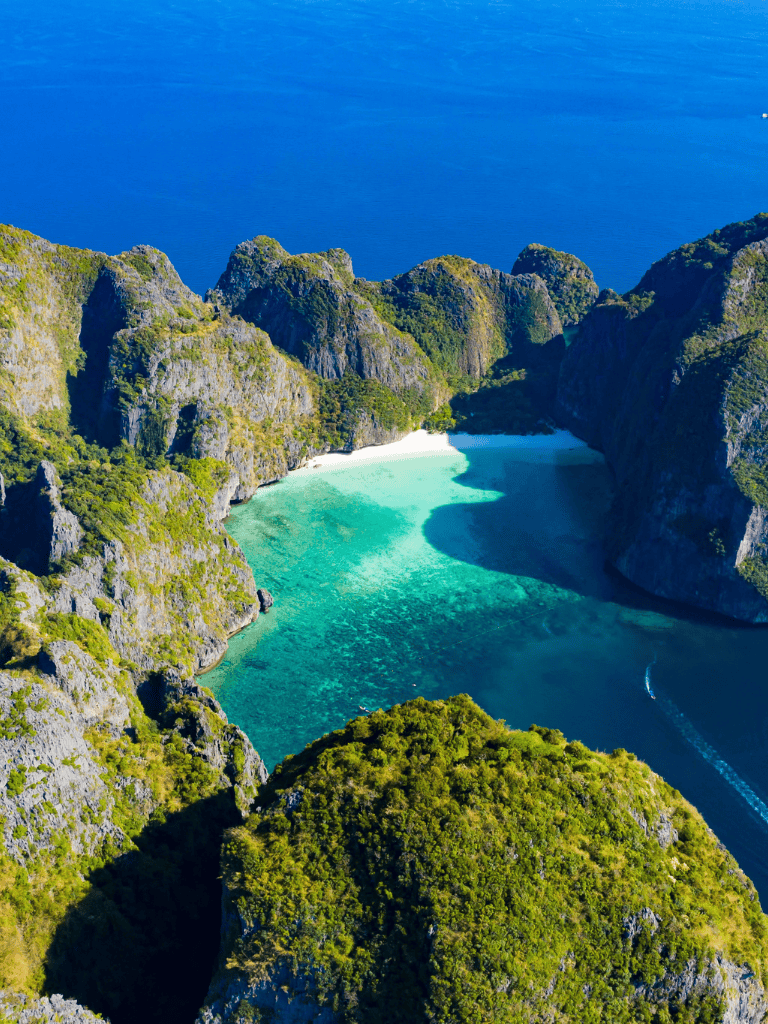 Breathtaking aerial view of hidden lagoon at Nac Pan, Thailand, surrounded by lush green cliffs and turquoise waters.