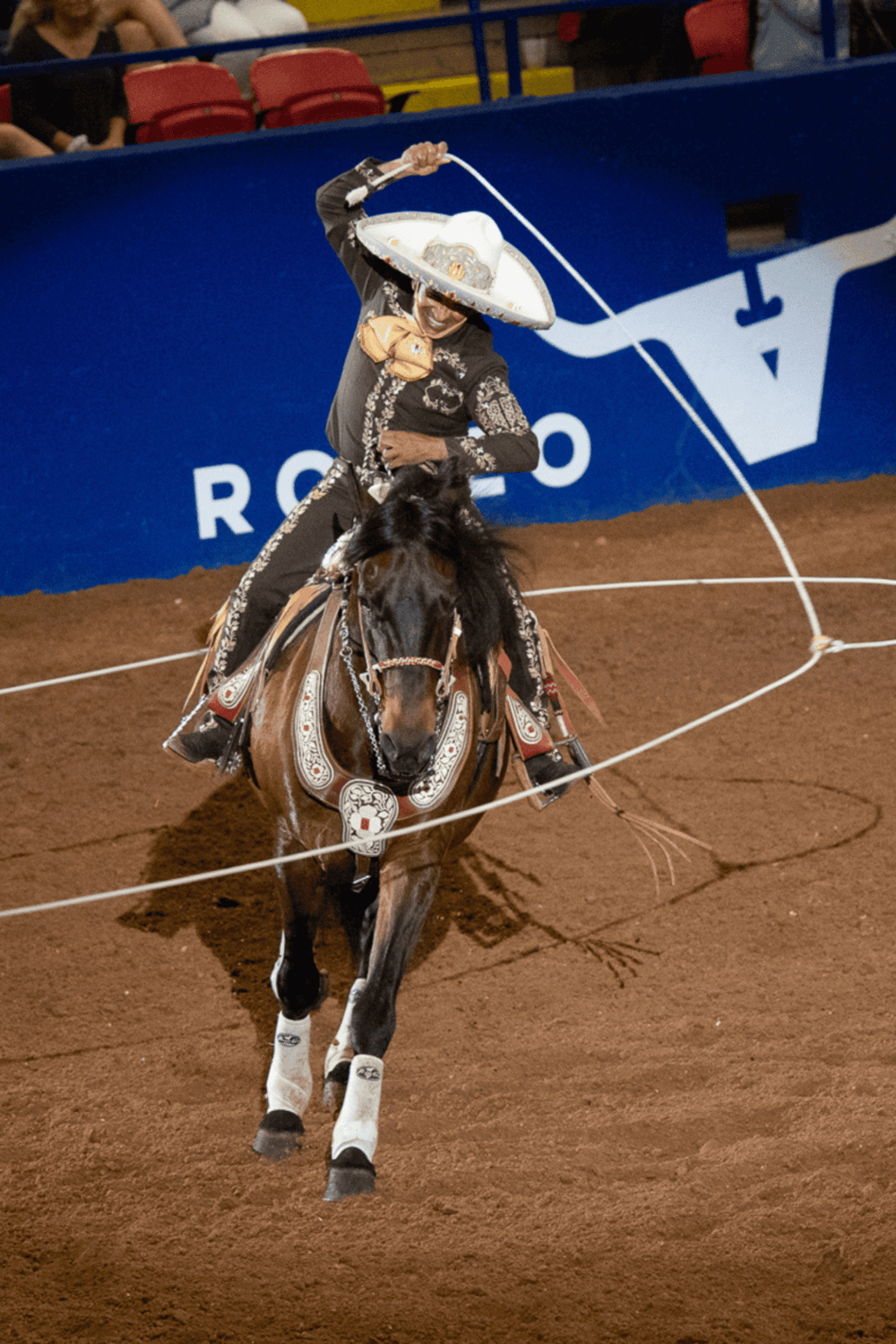 Rodeo cowboy performing lasso tricks during an indoor rodeo event at QuestForDirections.
