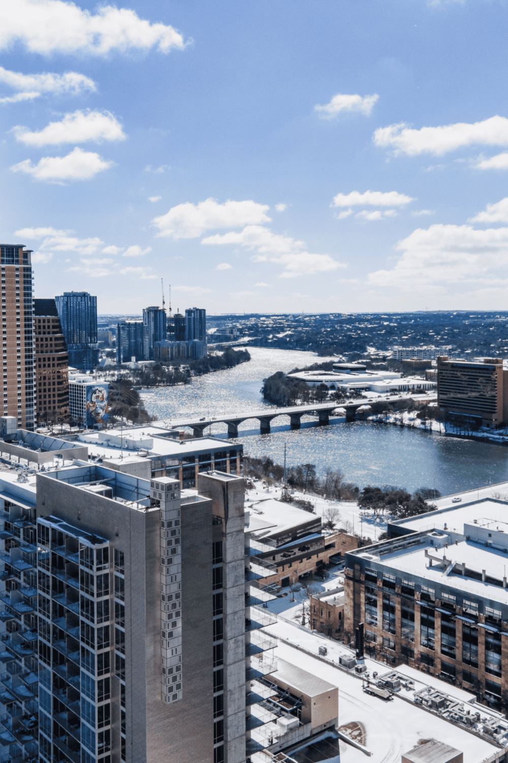 Aerial view of downtown cityscape with river and bridges during winter, showcasing skyscrapers and urban development.