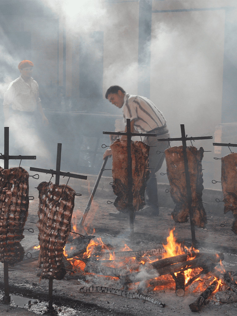 Sizzling barbecue with hanging meats over open flames at QuestForDirections event.