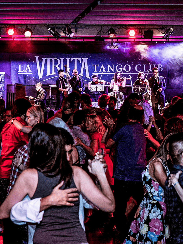 Elegant tango dance performance at La Viruta Tango Club with lively dancing crowd.