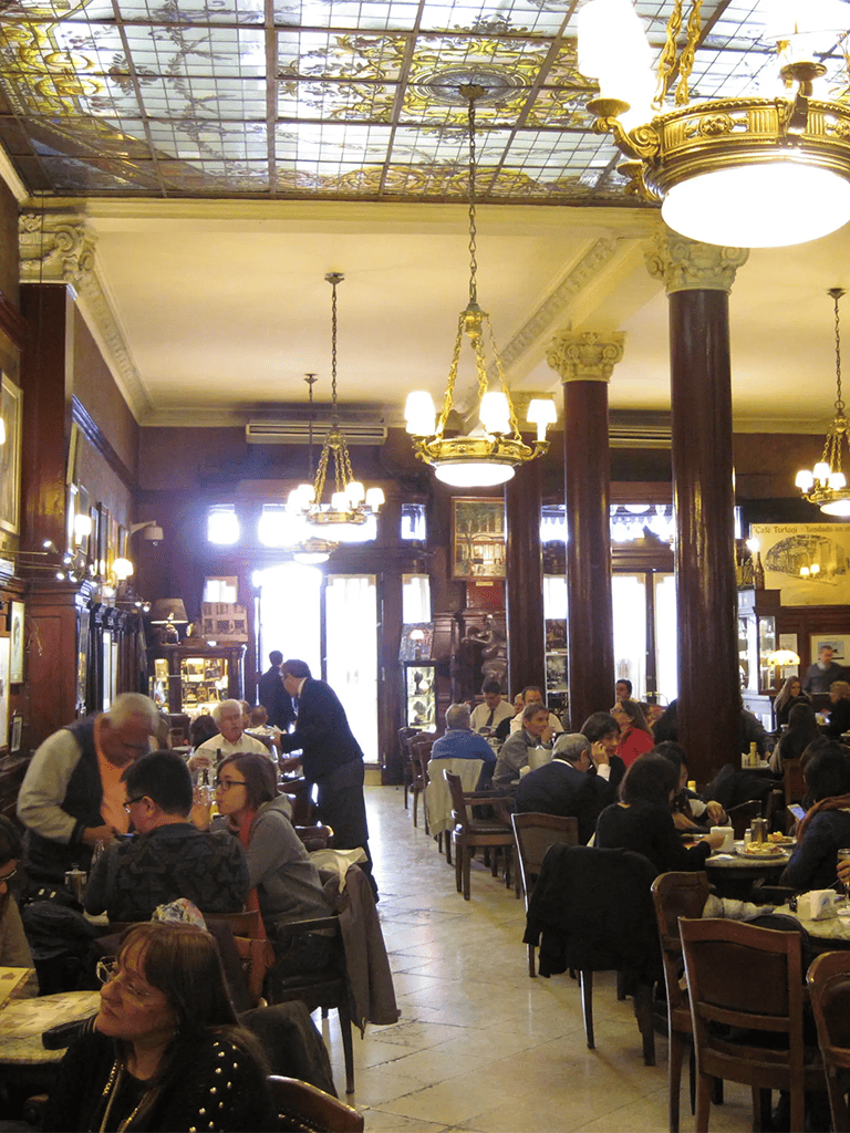 Elegant historic interior of QuestForDirections restaurant with chandeliers and busy diners.