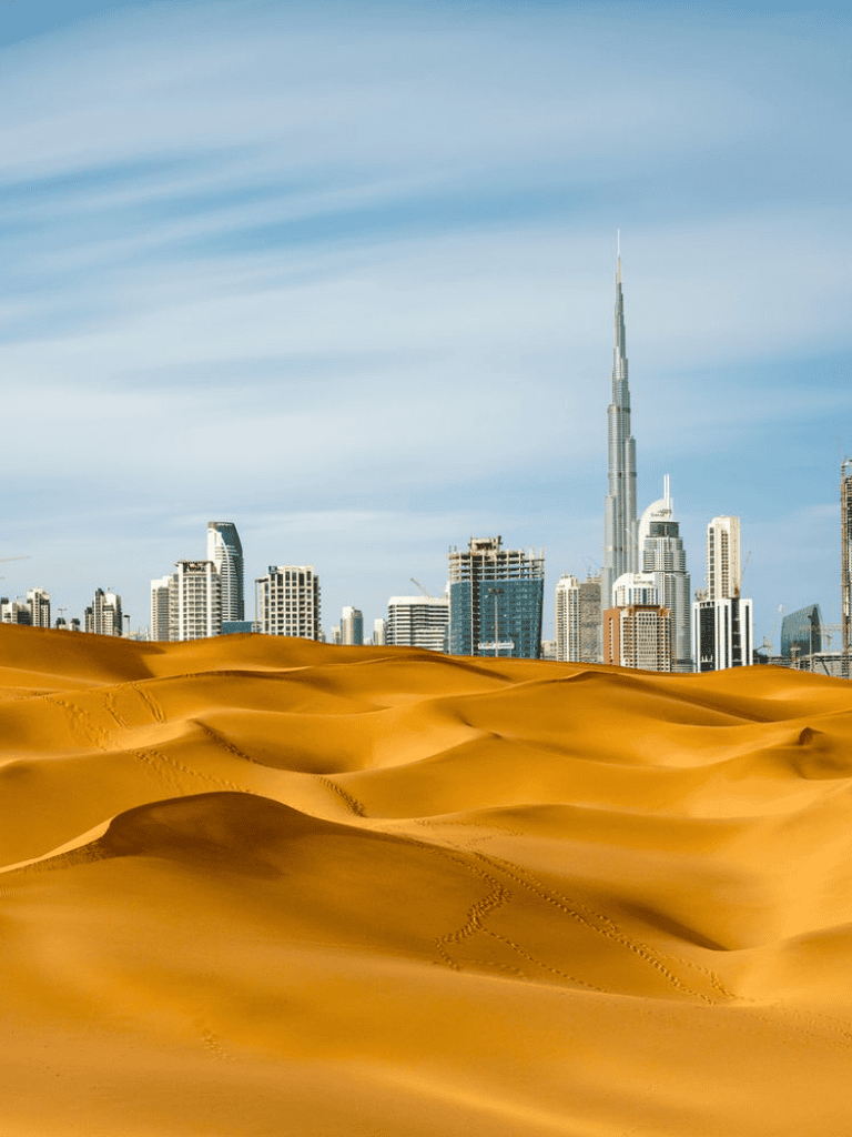 Desert dunes with Dubai skyline and Burj Khalifa in background, travel adventure, urban and desert landscape.