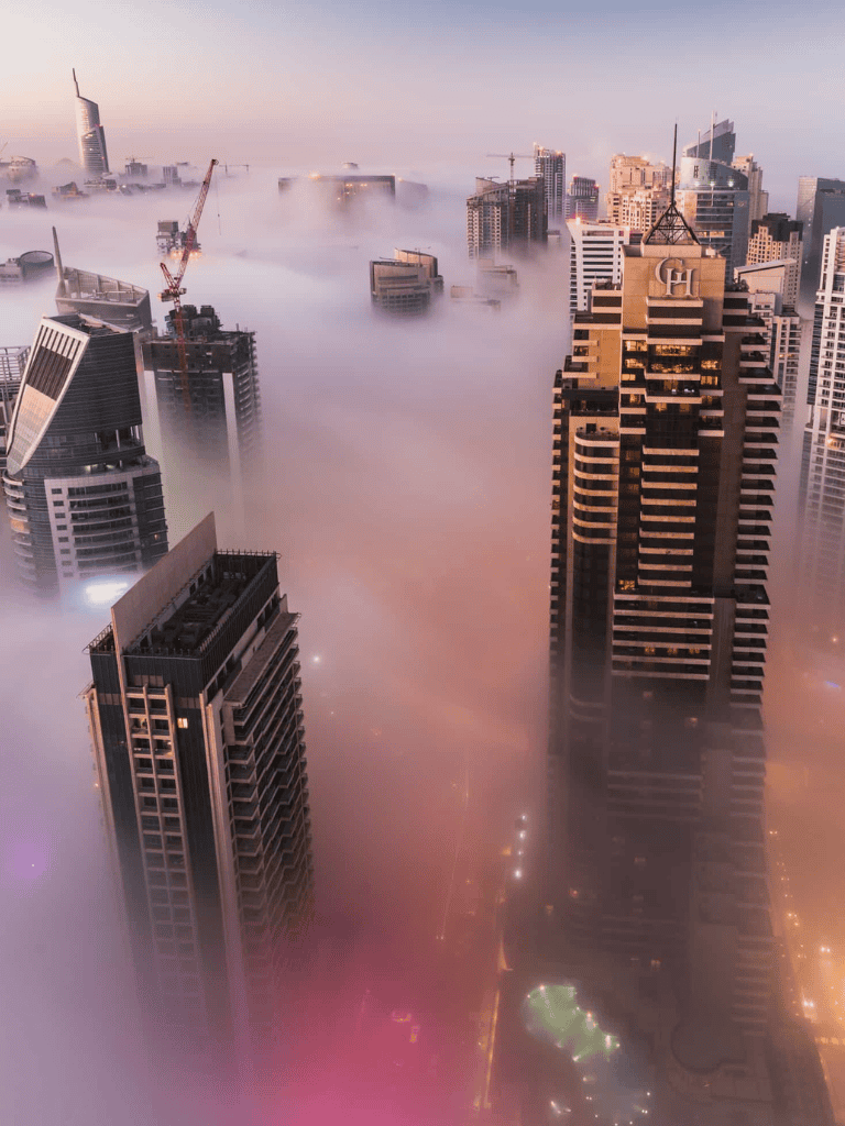 Cloudy city skyline with skyscrapers and fog in downtown area.