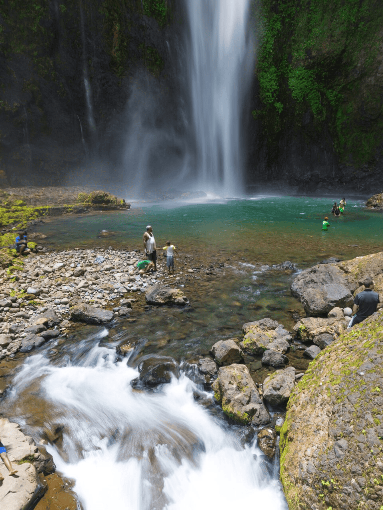 Breathtaking waterfall with clear turquoise water and visitors enjoying nature’s beauty.