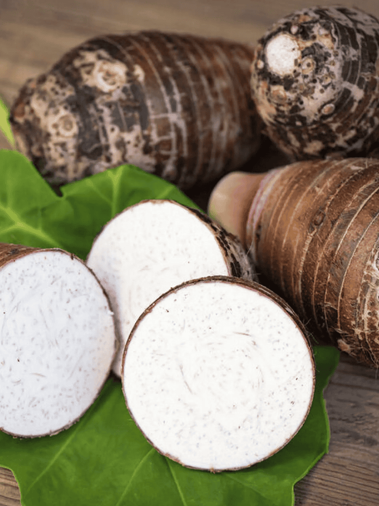 Soft taro root on fresh green leaf with sliced pieces, natural food ingredients, healthy vegetarian snack.
