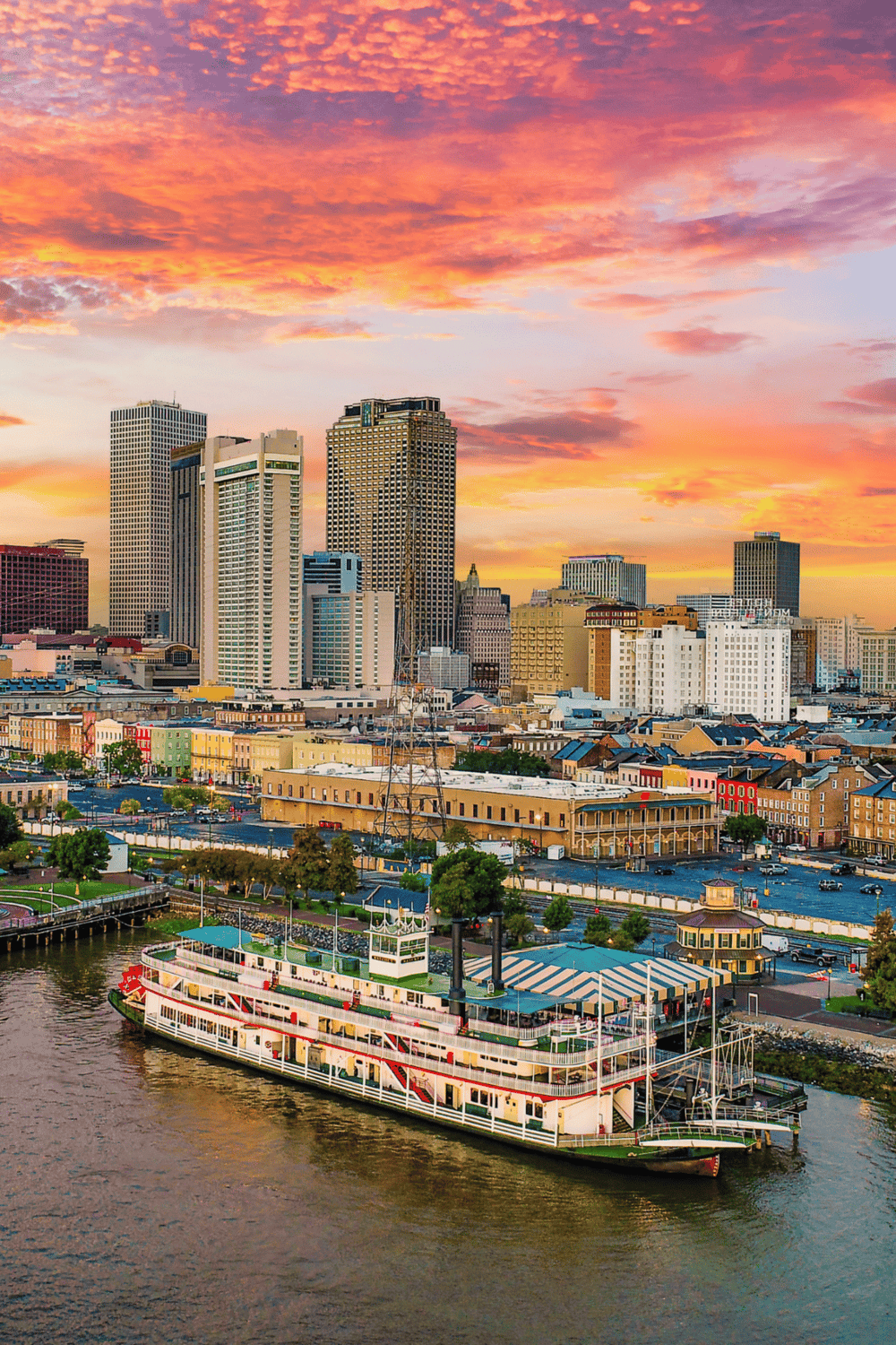 Colorful city skyline at sunset with boat cruise on river, downtown New Orleans, Louisiana.