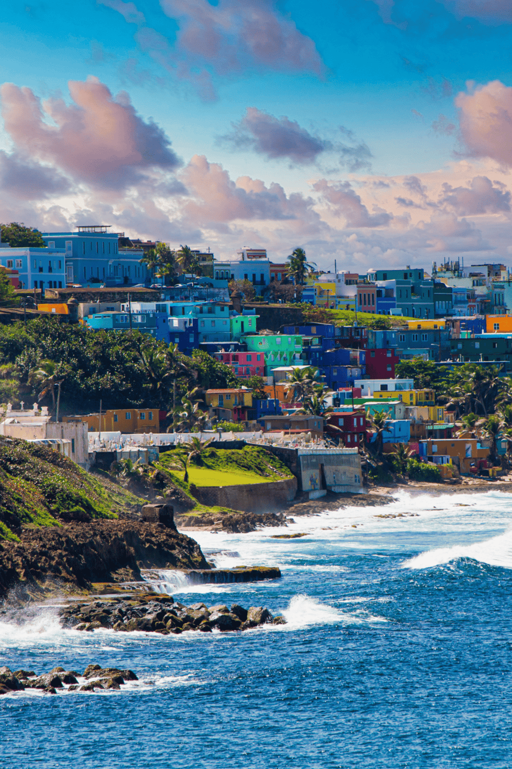 Colorful hillside town on the coast with vibrant houses and ocean waves, perfect for travel planning.