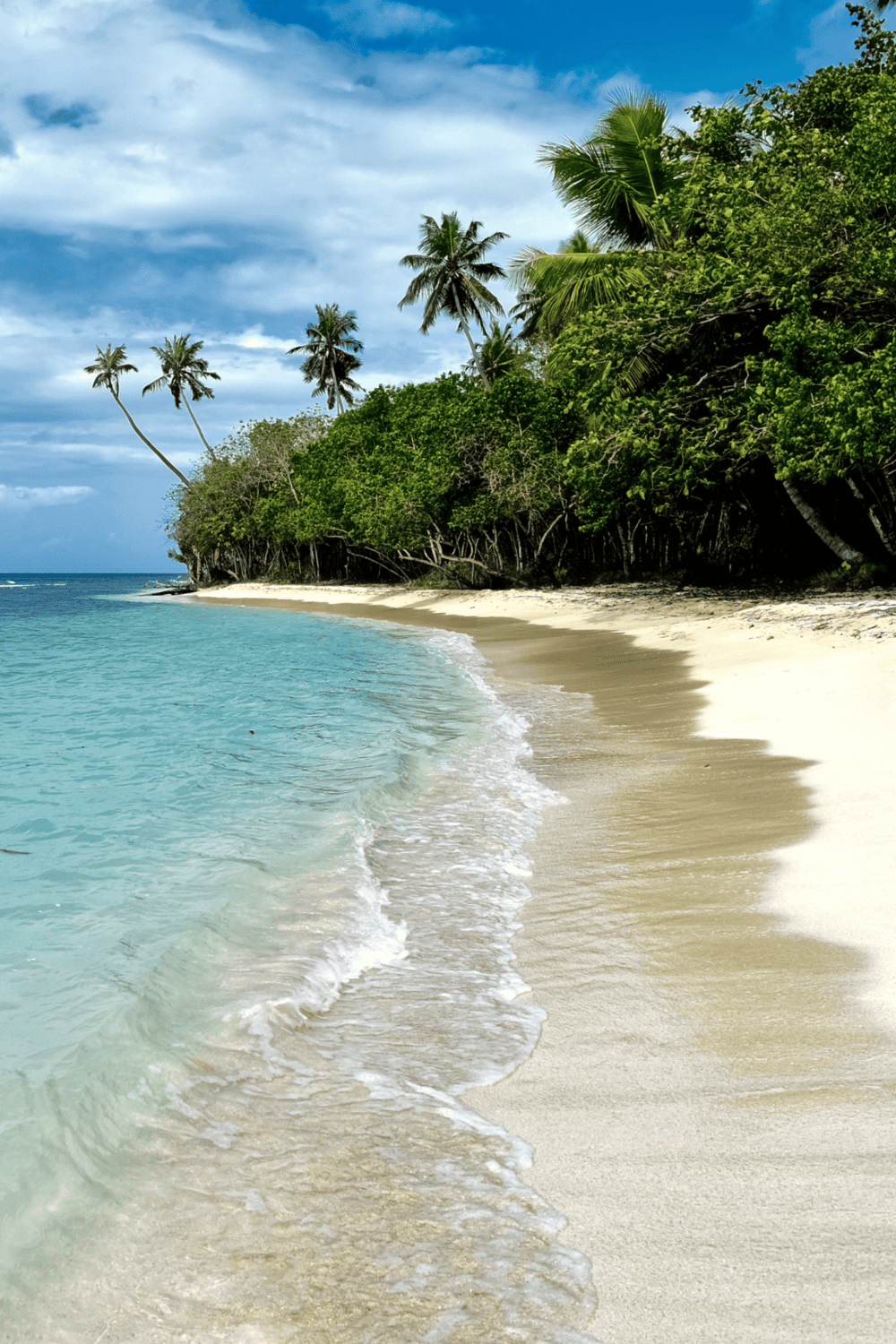 Pristine tropical beach with turquoise waters and lush greenery, perfect for vacation and relaxation.
