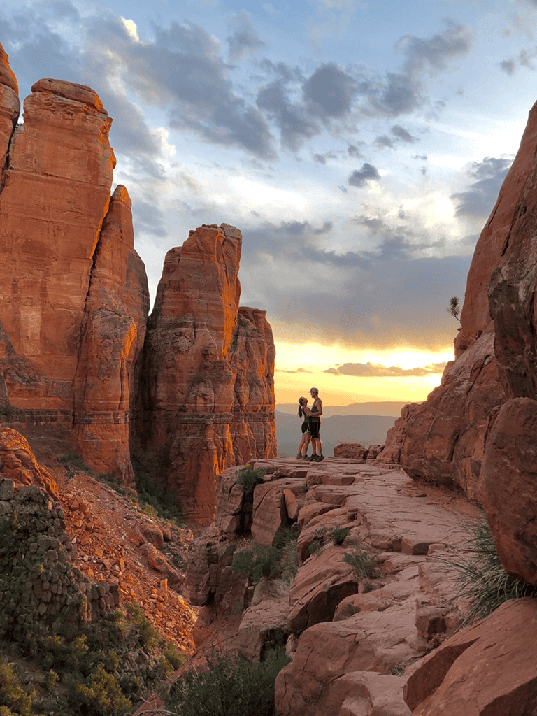 Breathtaking view of red rock formations at sunset with hikers exploring the trail.