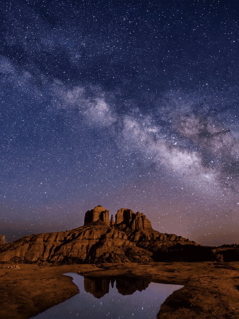 Stargazing under the Milky Way over desert rock formations at night.