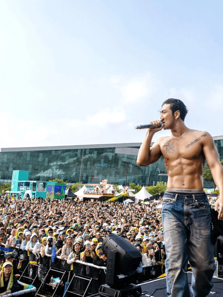 Charming male singer performing at outdoor music festival with large crowd, live entertainment, and vibrant festival atmosphere.
