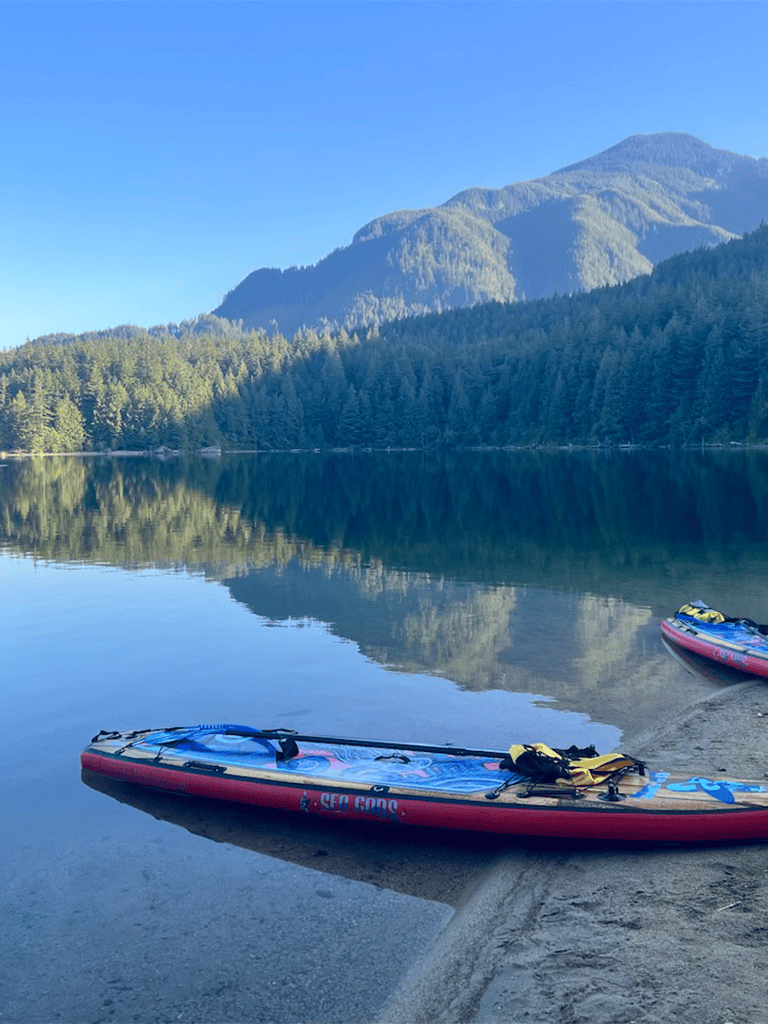 Serene mountain lake with kayaks, scenic nature, and lush forest background.