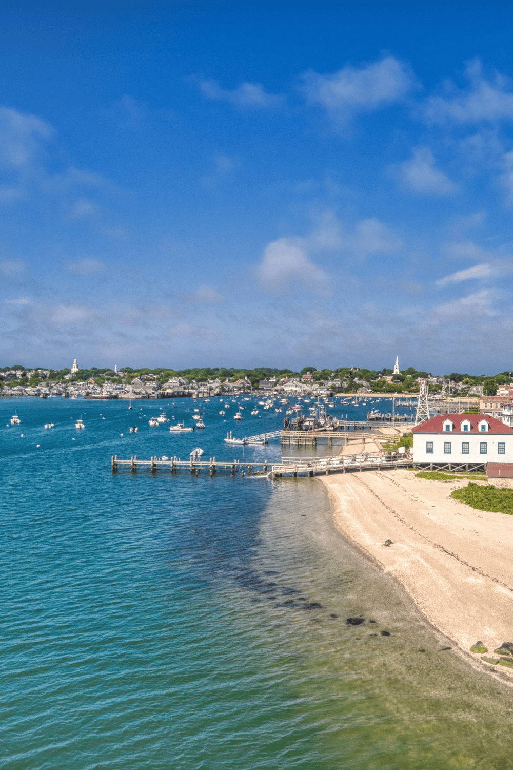 Sunny seaside harbor with boats and a sandy beach, perfect for coastal navigation and destination planning.