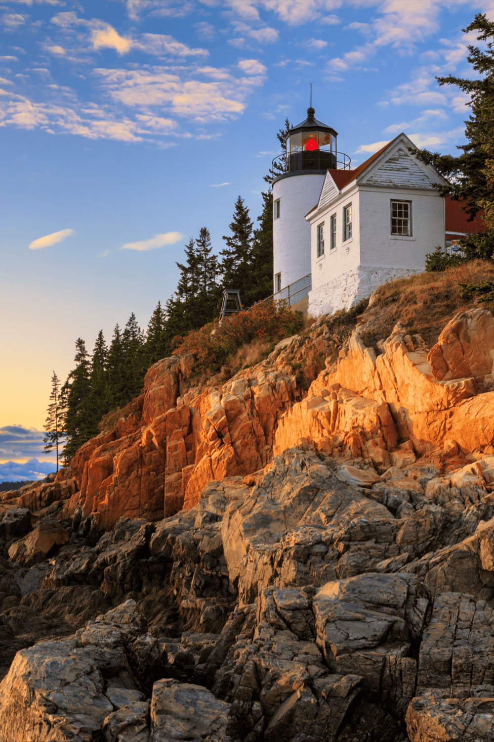 Lighthouse on rocky coastline at sunset, scenic coastal navigation, navigation aid and maritime safety.