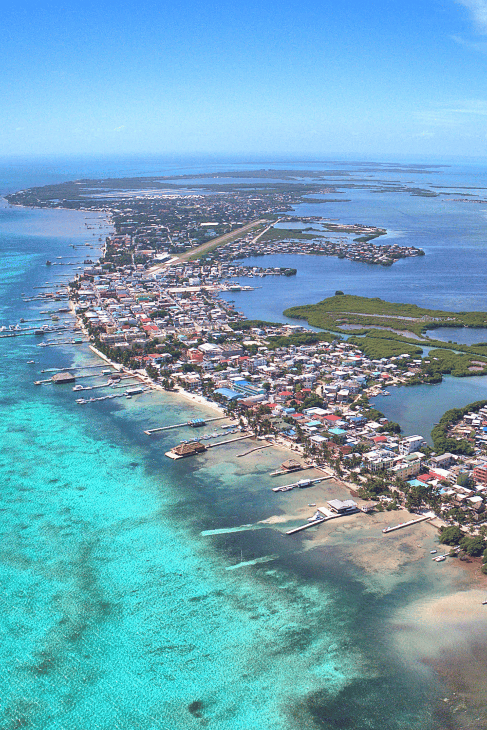 Aerial view of a seaside town with docks, beaches, and lush greenery, highlighting travel and navigation in coastal destinations.