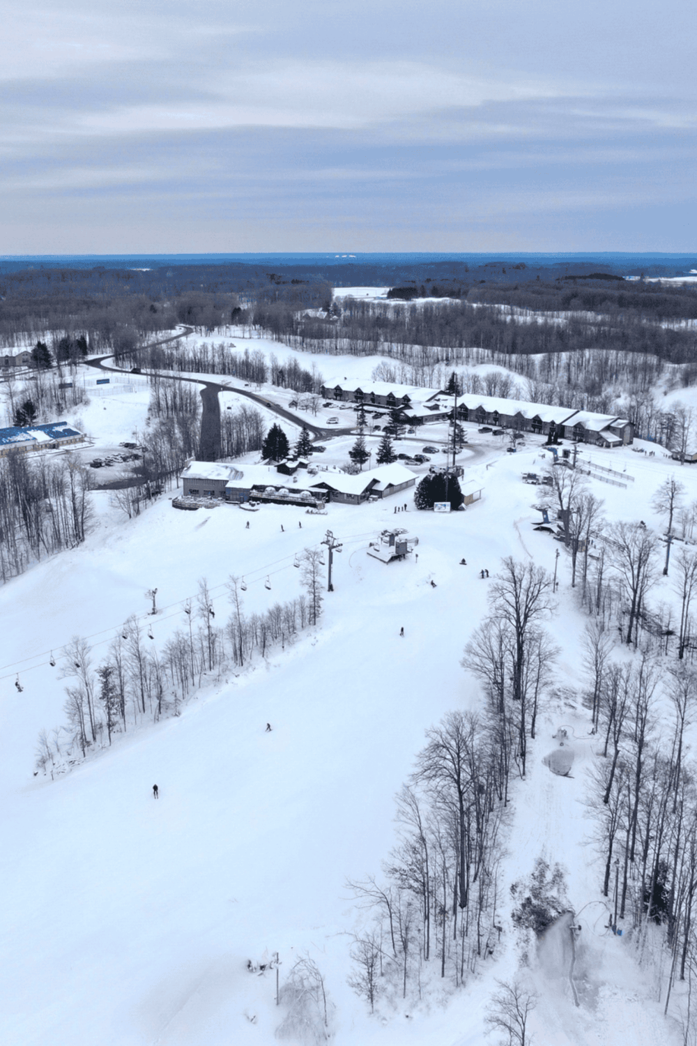 Snow-covered ski resort with chairlifts and ski trails in winter landscape.