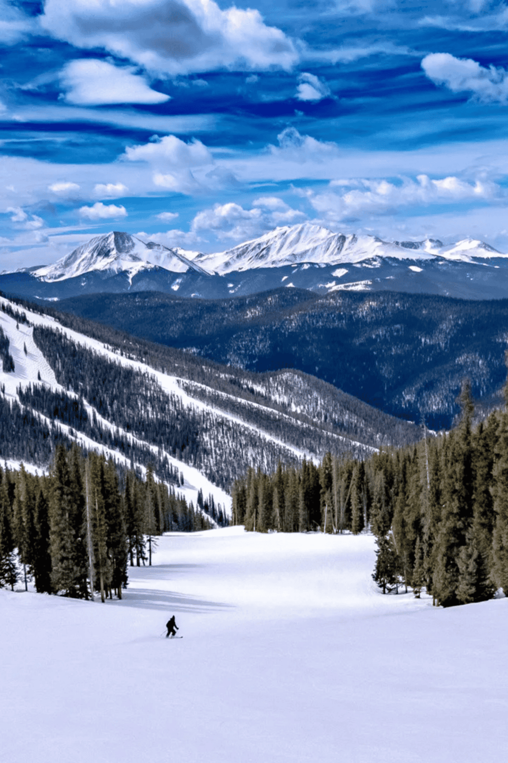 Snow-covered mountain landscape with skier, scenic winter outdoor adventure.