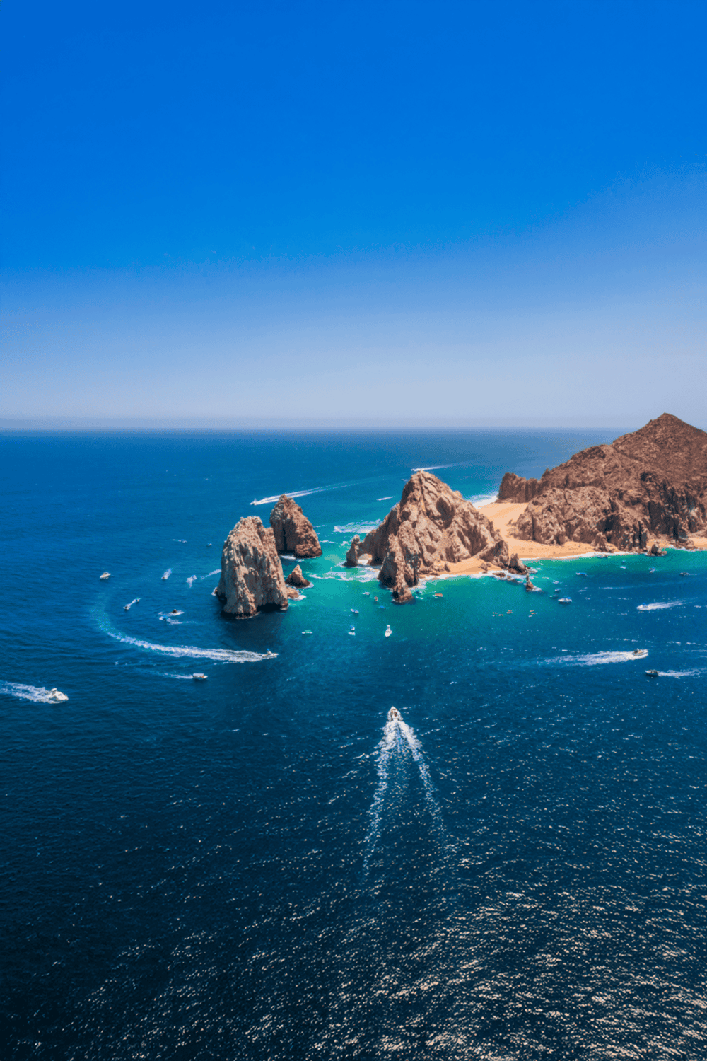 Stunning aerial view of a coastal island with rocky formations and turquoise waters, perfect for travel planning and outdoor adventures.