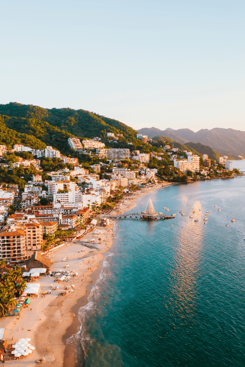 Vibrant beach cityscape with mountains, ocean, and modern buildings in Cabo San Lucas.